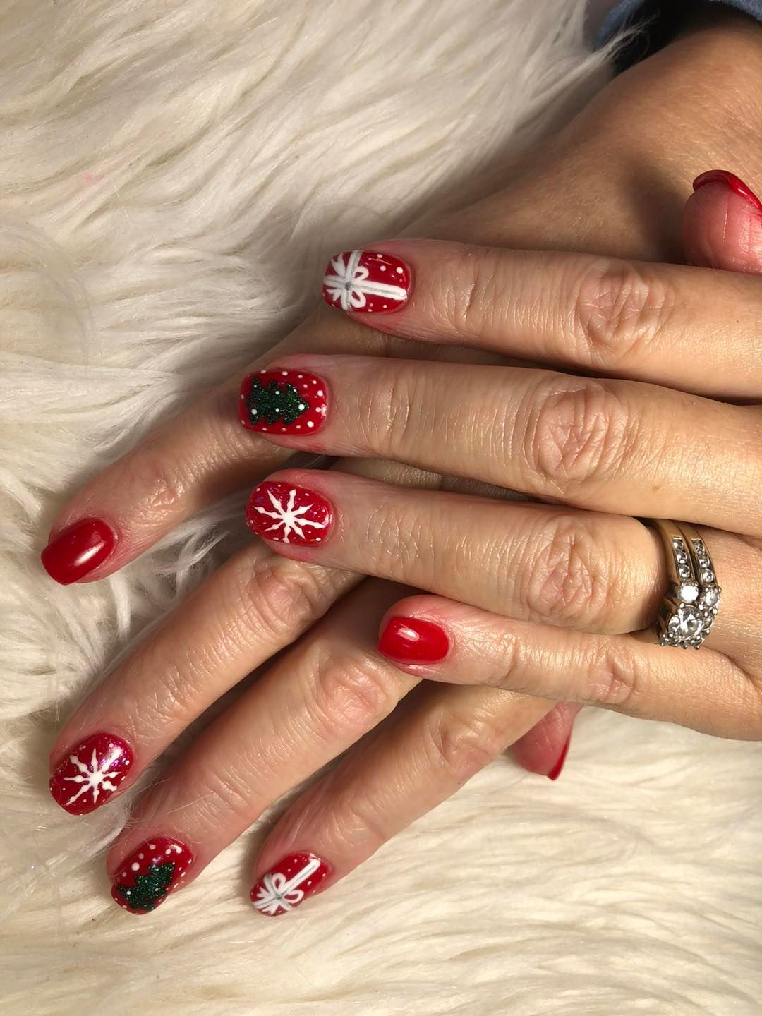 A close up of a woman 's hands with red nails and a ring.