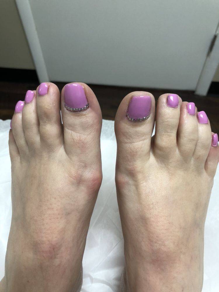 A close up of a person 's feet with purple toenails.