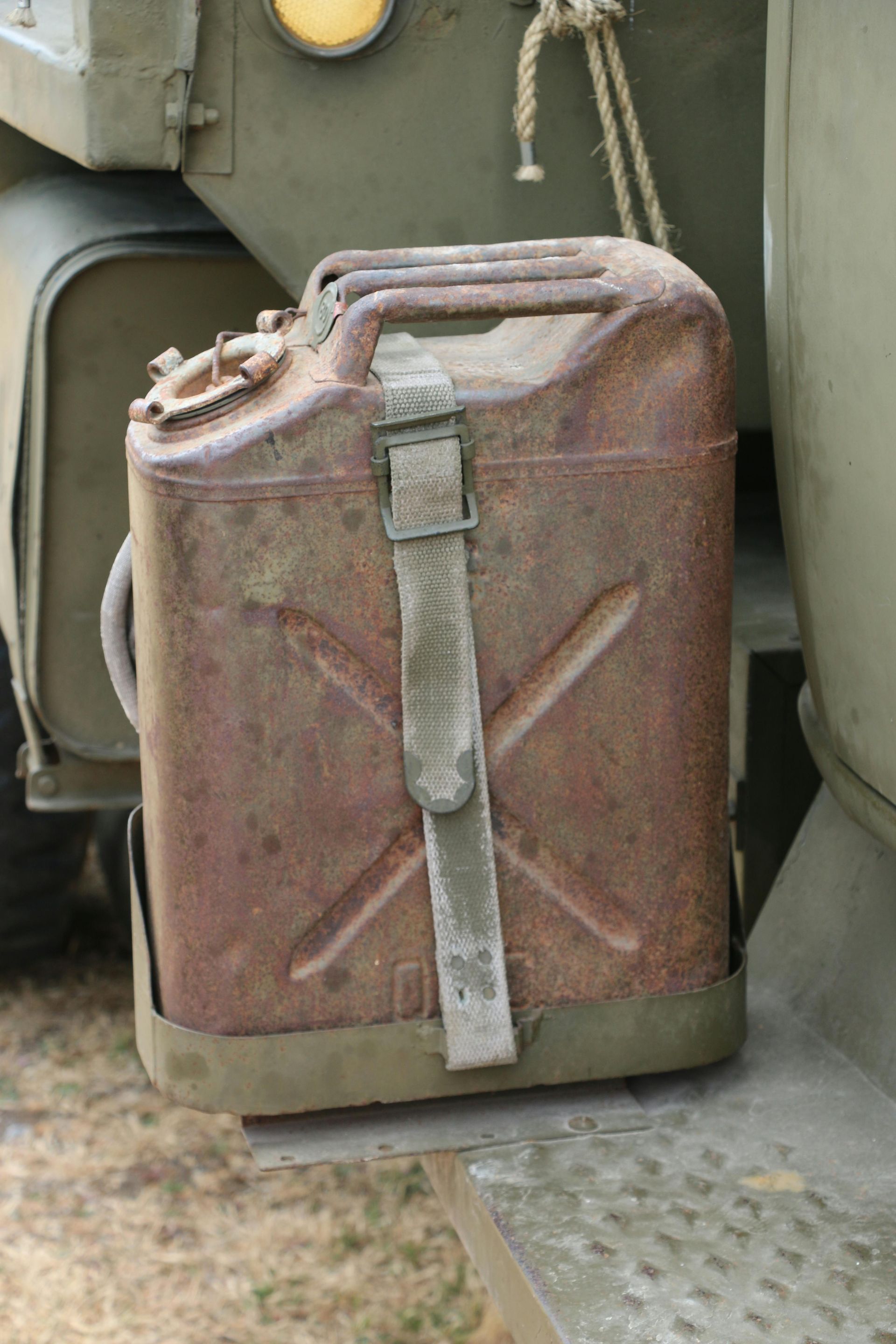 Rusty metal fuel canister, strapped to a military vehicle.