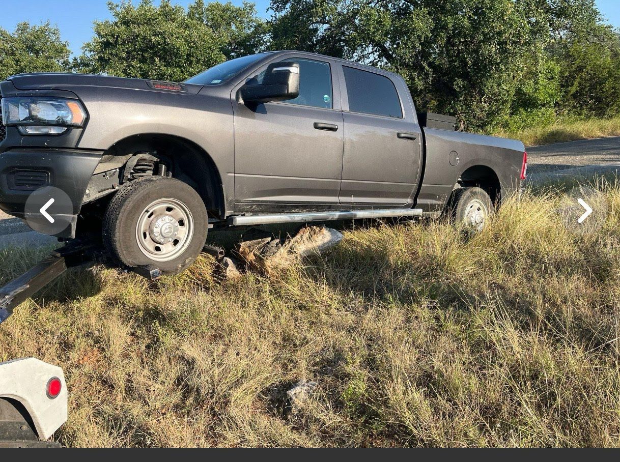 Gray pickup truck stuck off the side of a road in a grassy area.