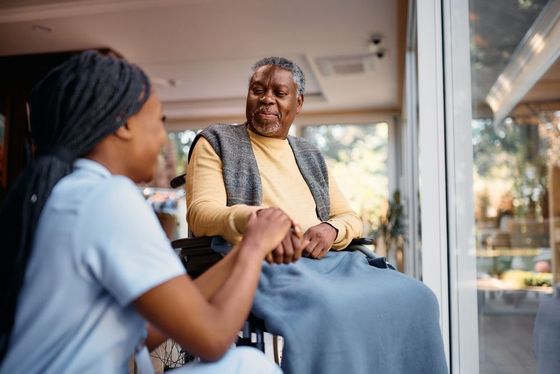 A nurse is talking to an elderly man in a wheelchair.