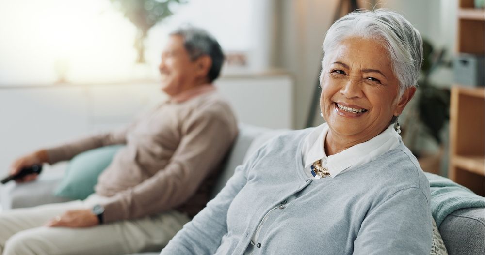 A woman is smiling while sitting on a couch next to a man.