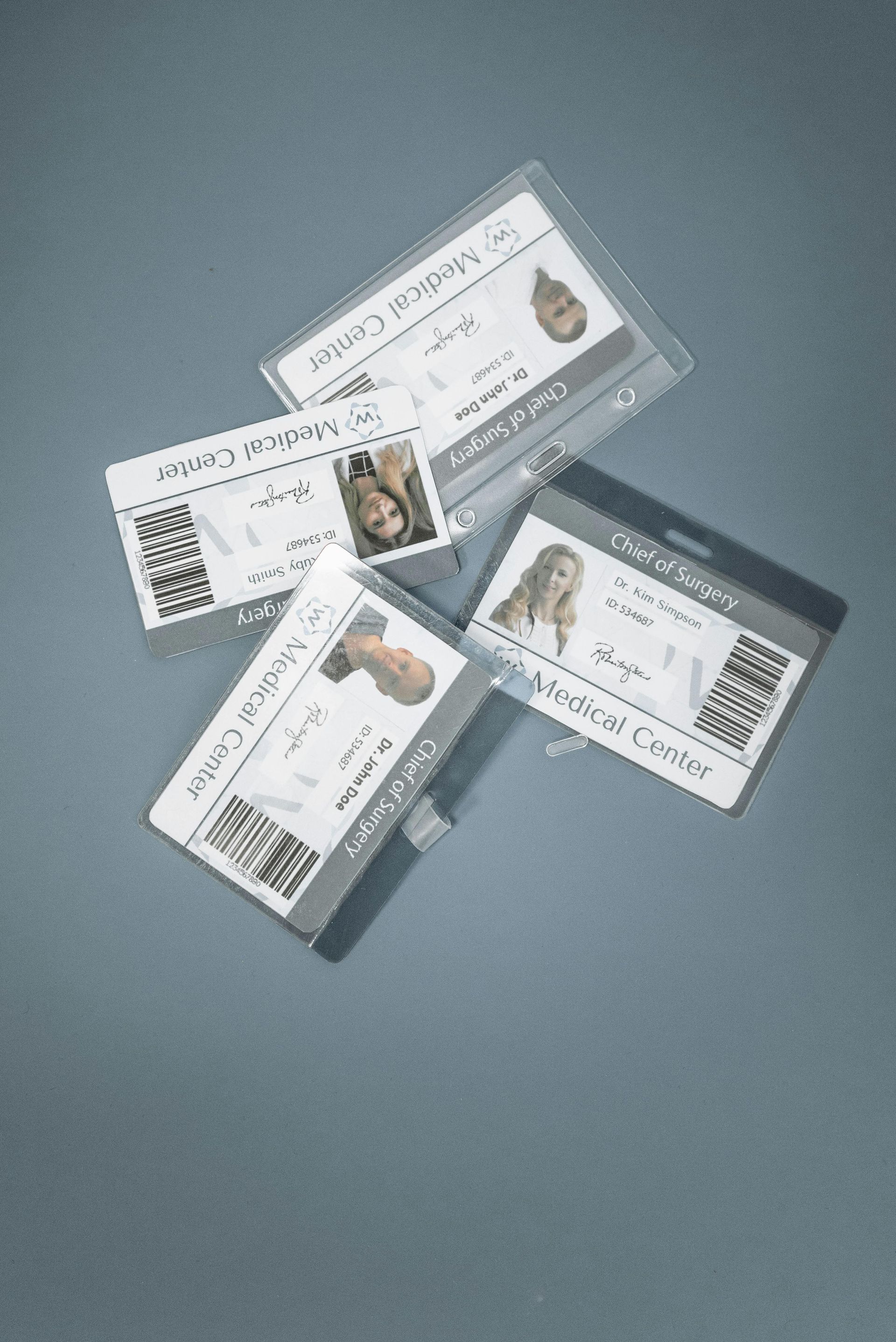 Three id cards are stacked on top of each other on a table.