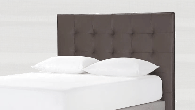 Cabecero capitoné marrón con ropa de cama y almohadas de color blanco.