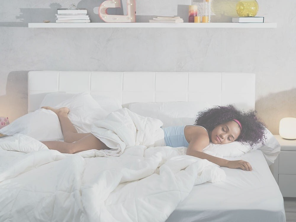 Mujer durmiendo en la cama, sábanas blancas, habitación acogedora, lámparas de noche, estante con decoración.