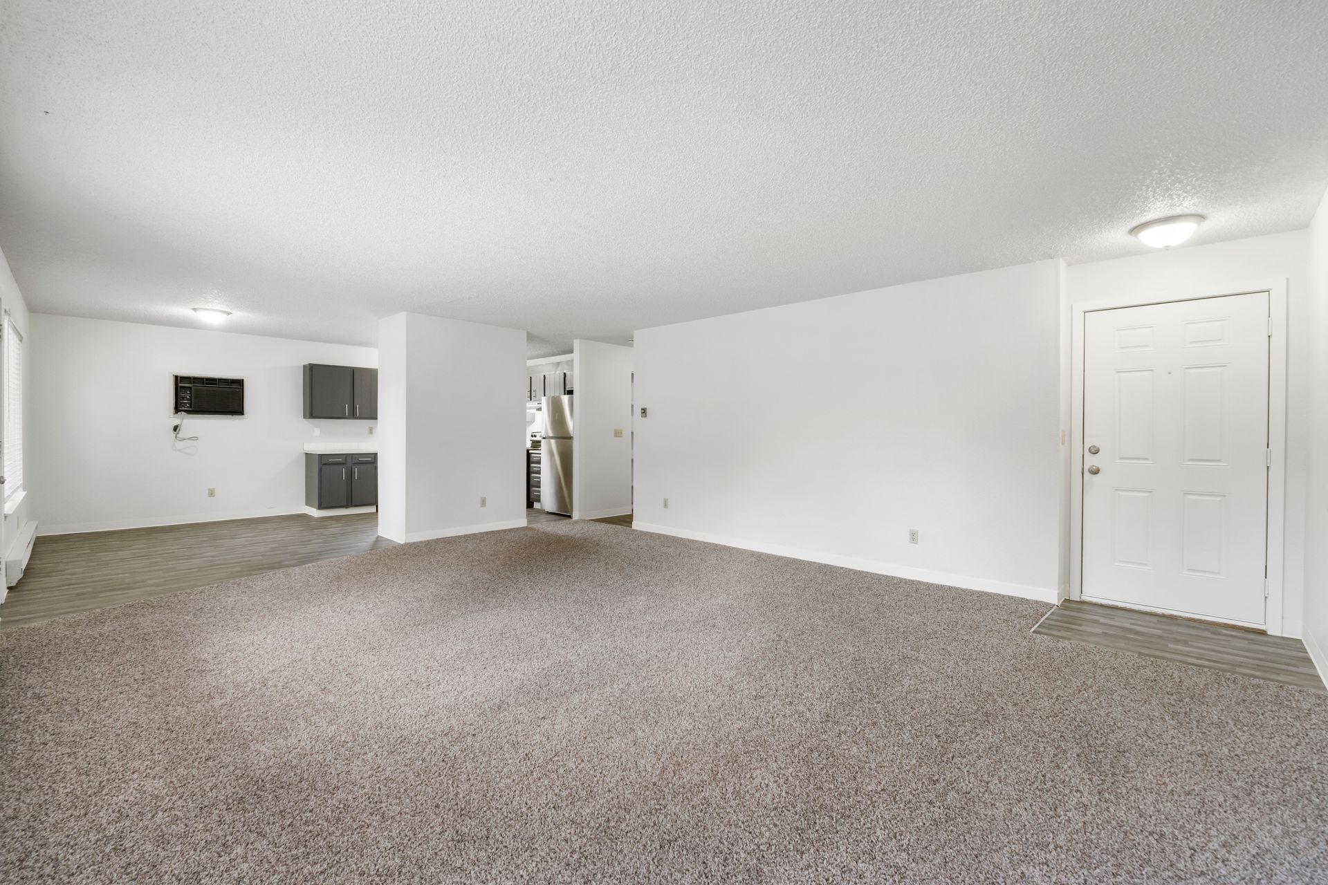 An empty living room with a carpeted floor and white walls.