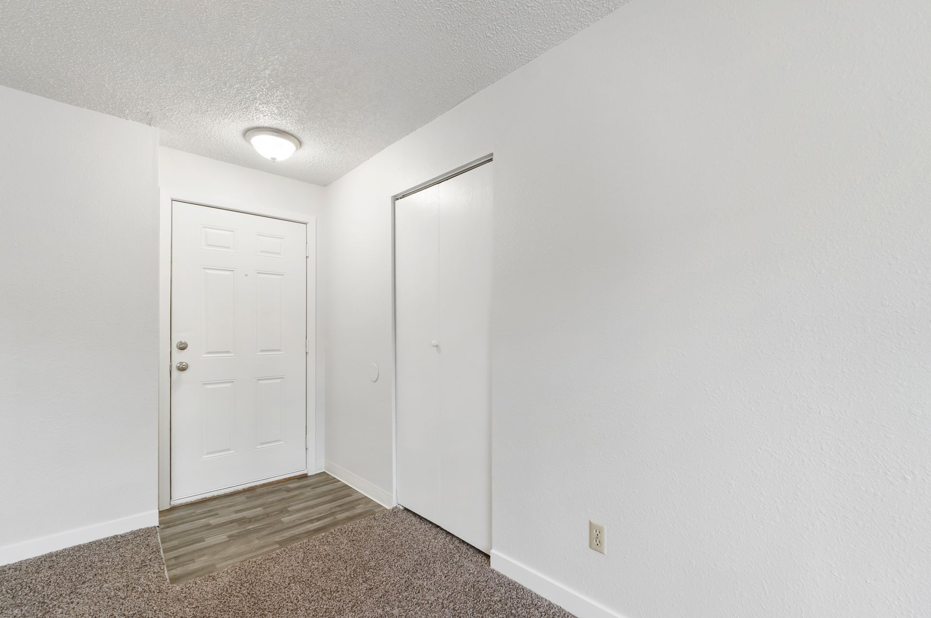 An empty room with a door and a closet.