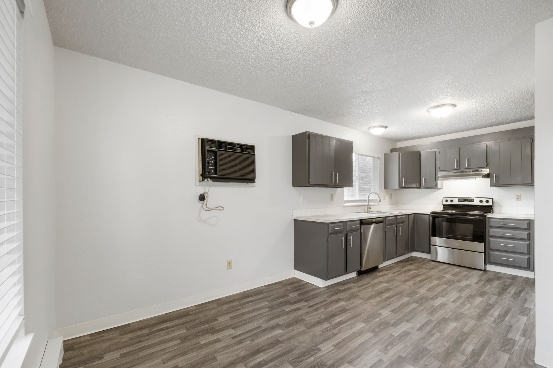 An empty kitchen with gray cabinets and stainless steel appliances