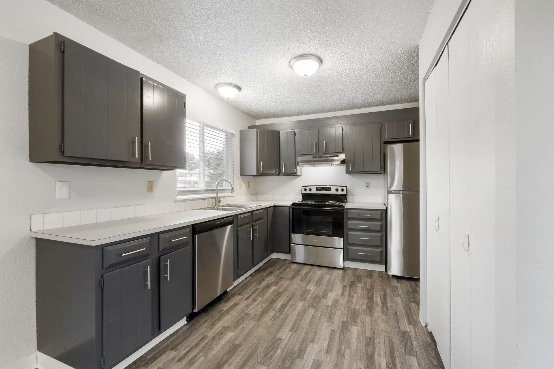 A kitchen with stainless steel appliances and gray cabinets.