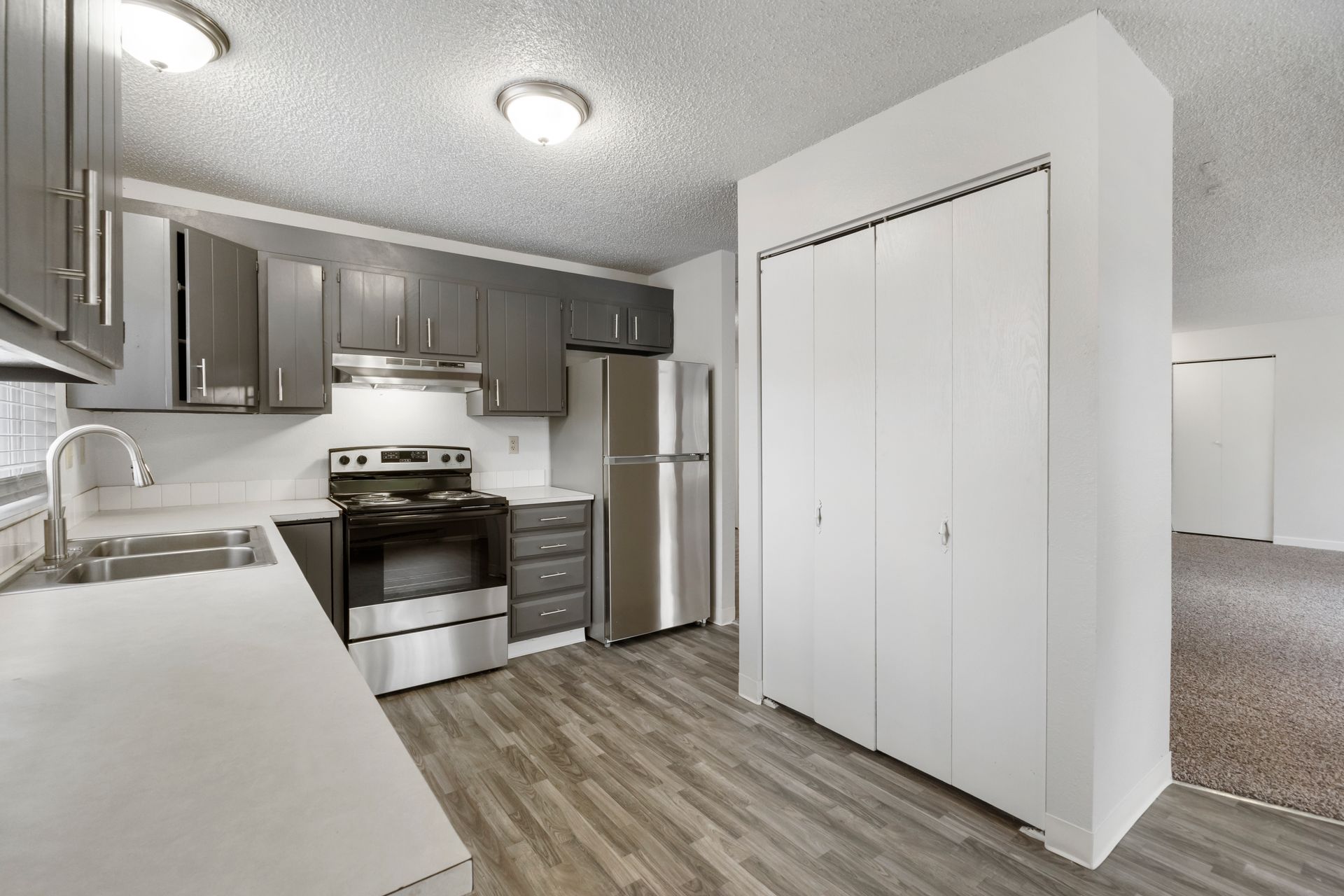 A kitchen with a stove , refrigerator , sink and cabinets.