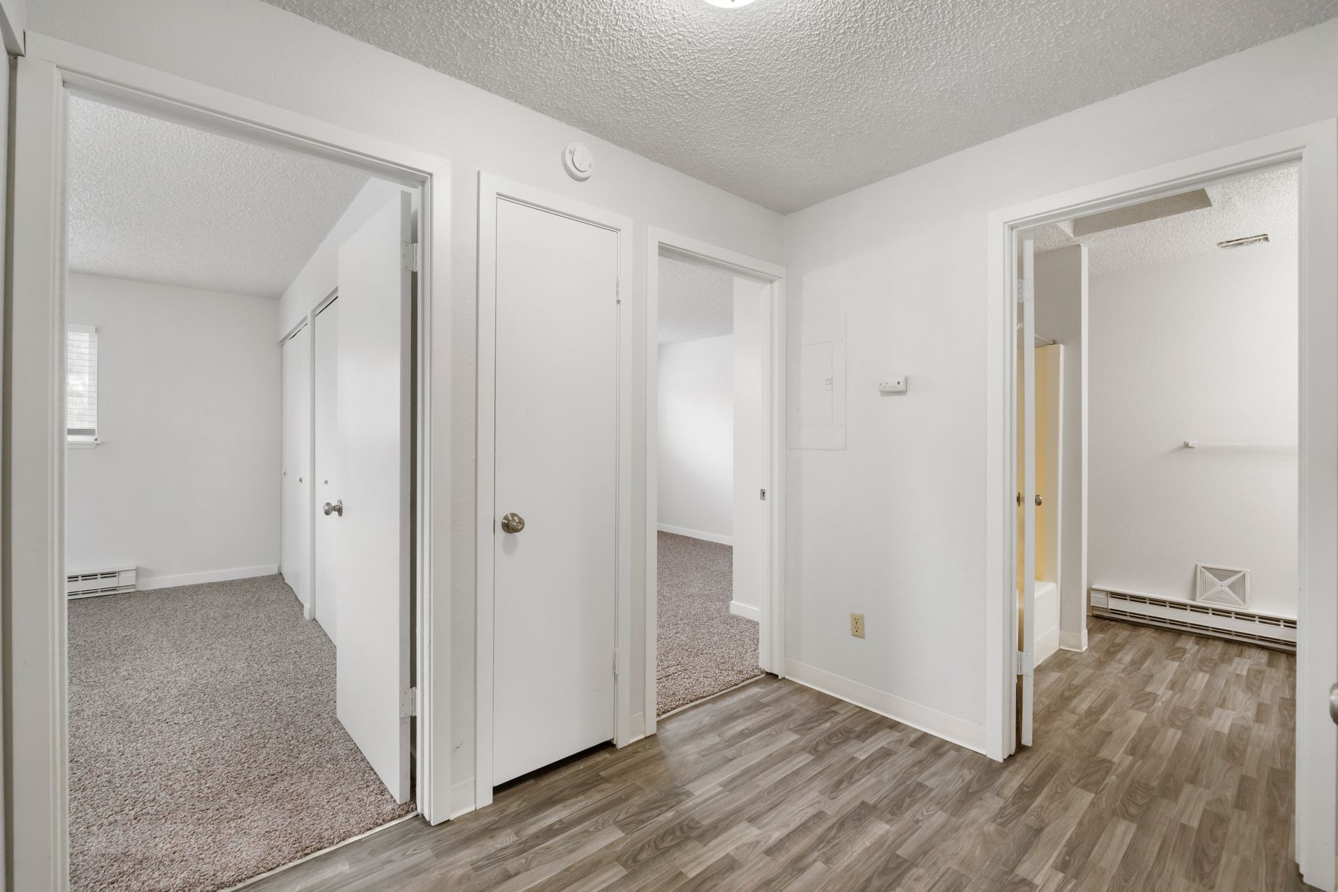 A hallway in a house with wooden floors and white walls.