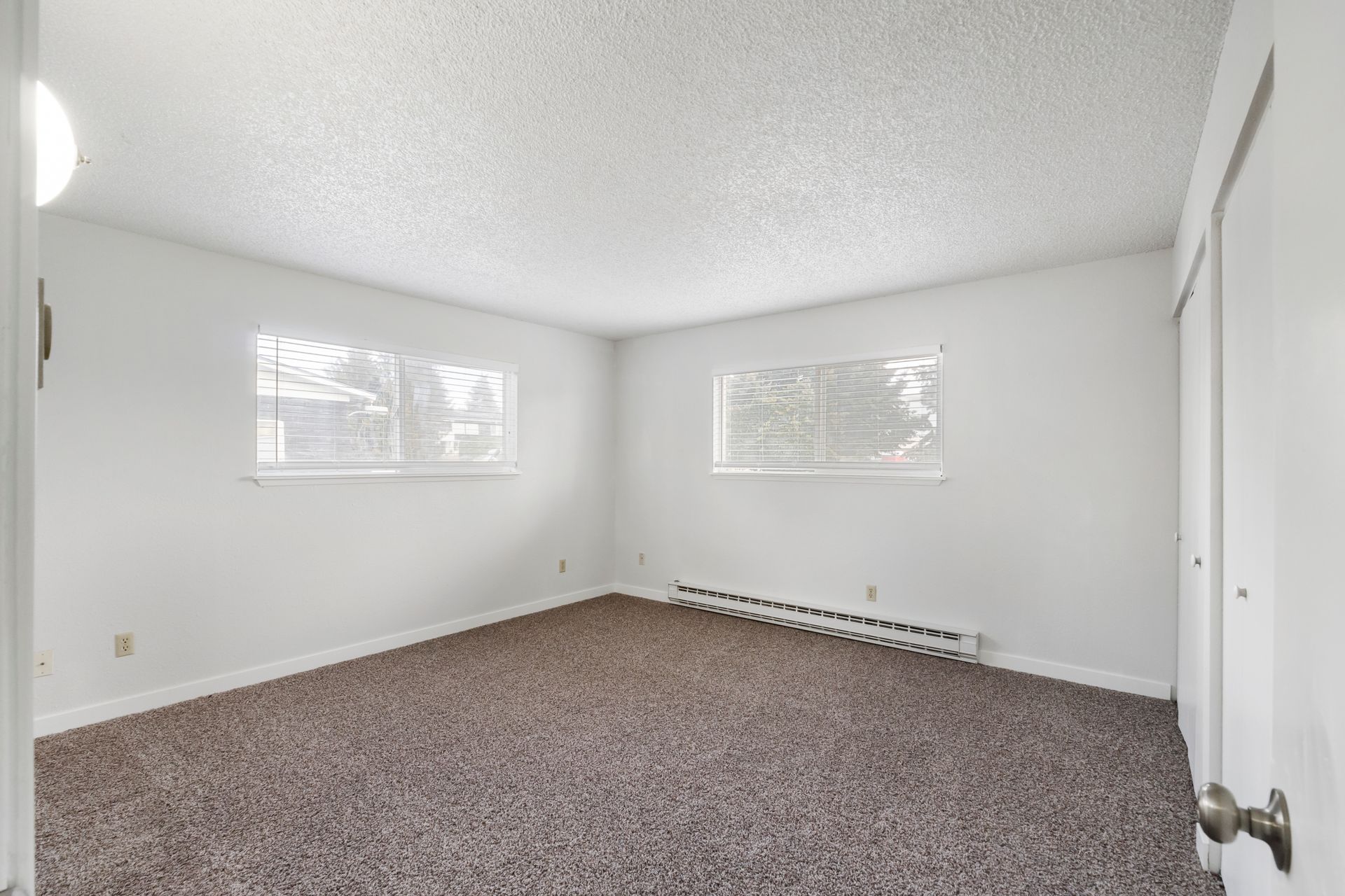 An empty living room with a carpeted floor and white walls.