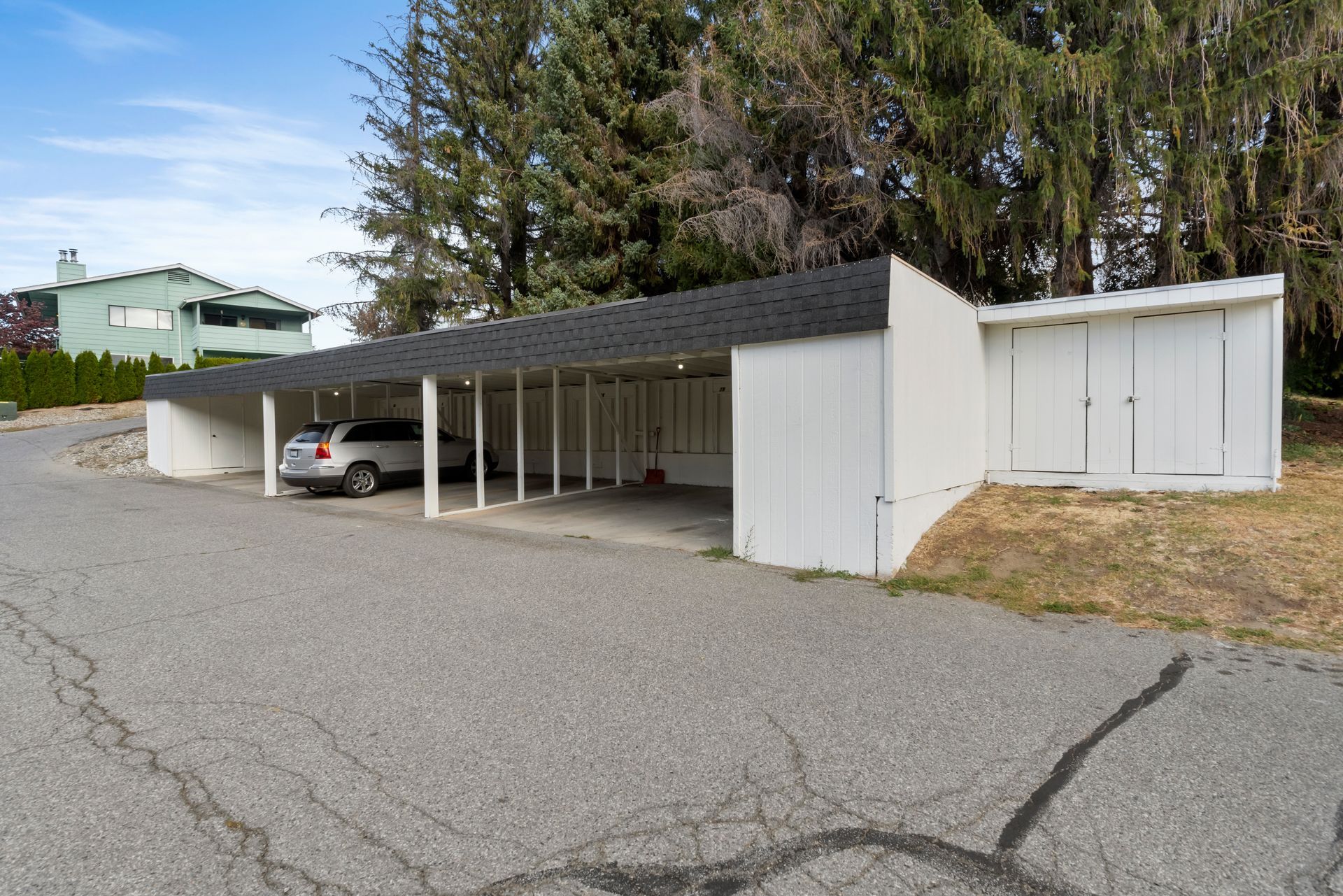 A car is parked under a carport in front of a house.