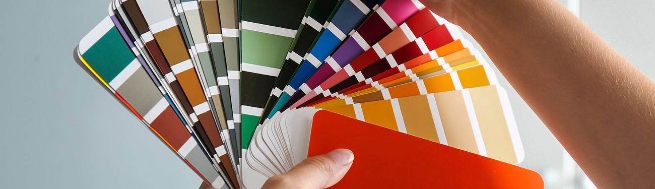 A person is holding a fan of color swatches.