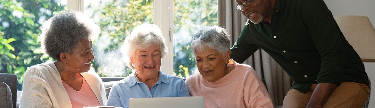 A group of elderly people are looking at a laptop computer.
