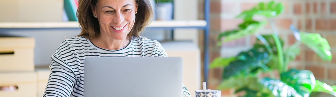 A woman is sitting at a desk using a laptop computer.