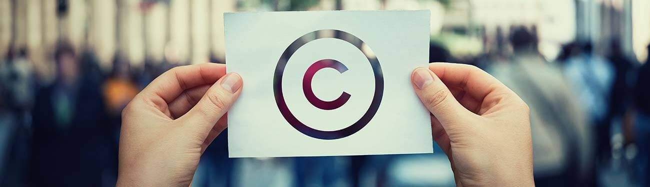 A person is holding a piece of paper with a copyright symbol on it.