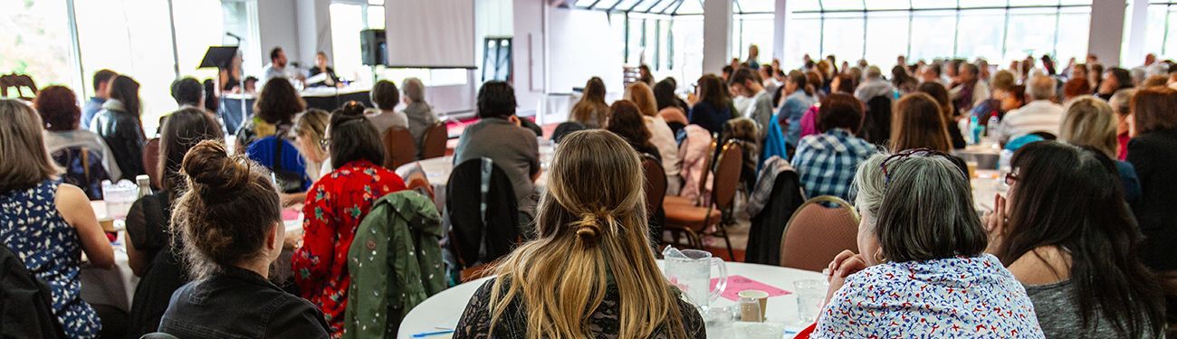 A large group of people are sitting at tables in a conference room.