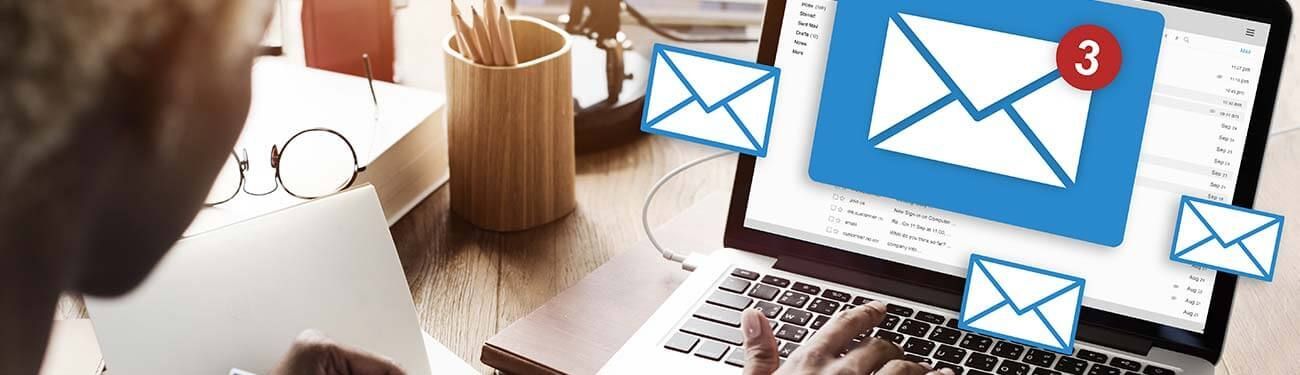 A man is typing on a laptop computer with an envelope on the screen.