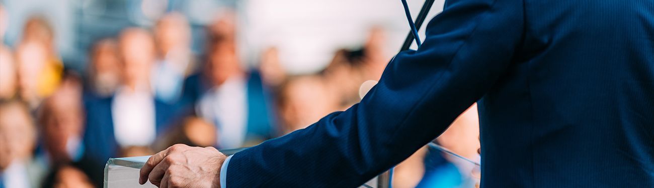 Tablet displaying graphics with additional images like newsletter covers and infographics layered in front. Blue background.