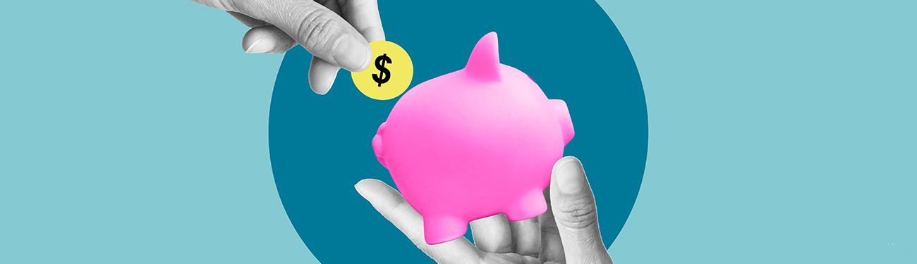 A person is putting a coin into a pink piggy bank.