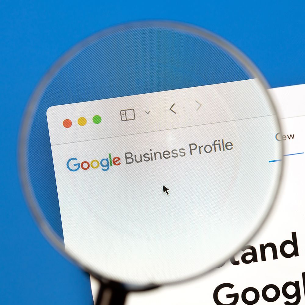 A magnifying glass focuses on the Google Business Profile webpage