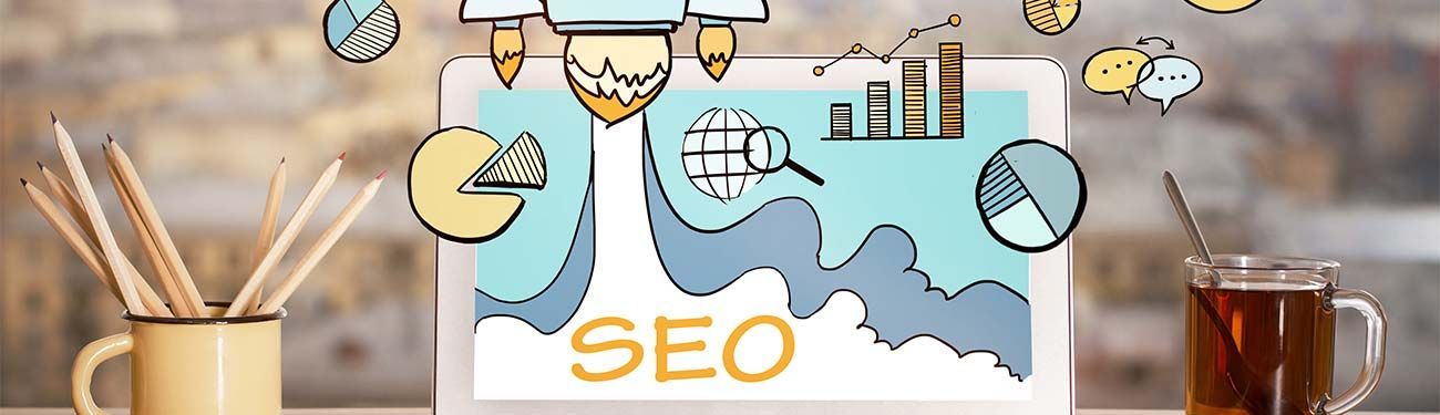 A laptop computer is sitting on a desk next to a cup of tea.