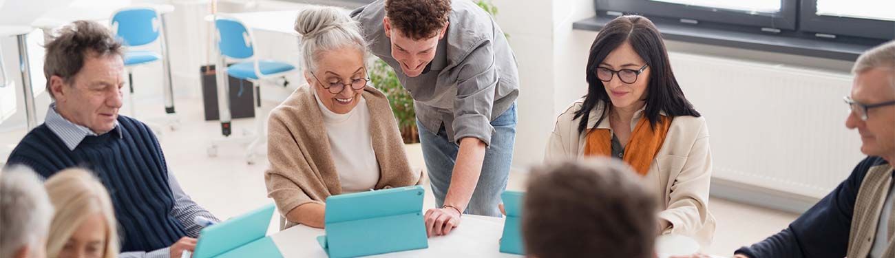 A group of people are sitting around a table looking at a laptop.
