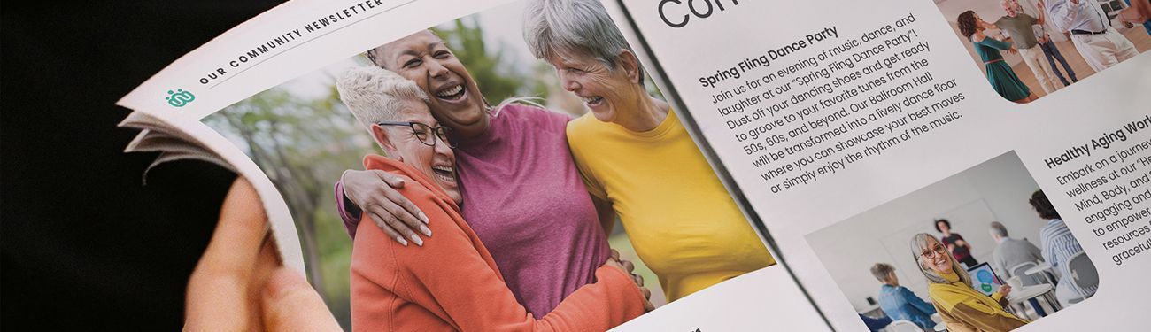 A person is holding a newspaper with a picture of three older women on it.
