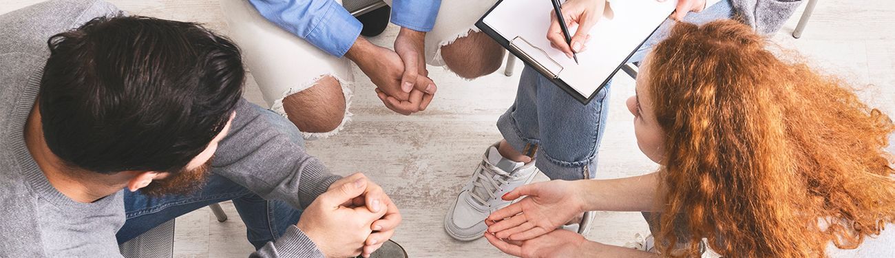 A group of people are sitting in a circle with their hands together.
