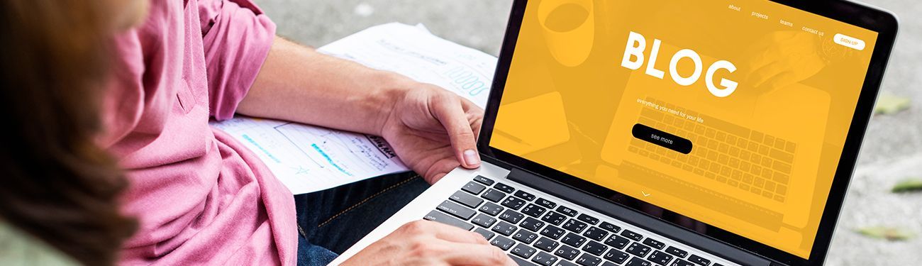 A person is using a laptop computer with the word blog on the screen.