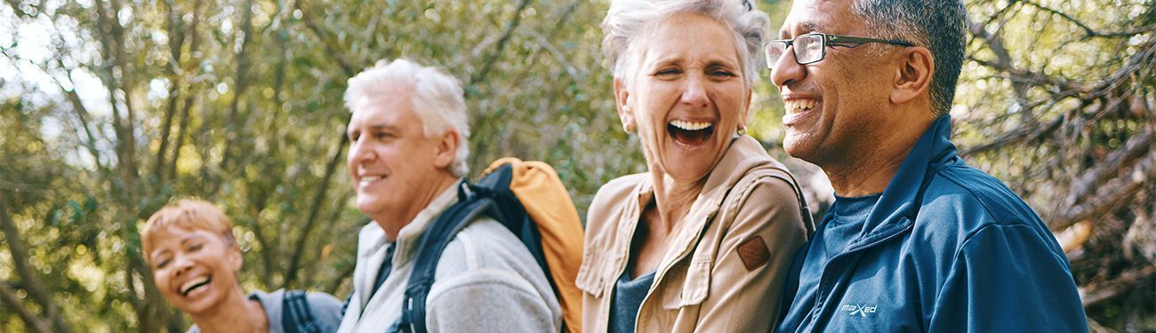 A group of elderly people are walking in the woods and laughing.