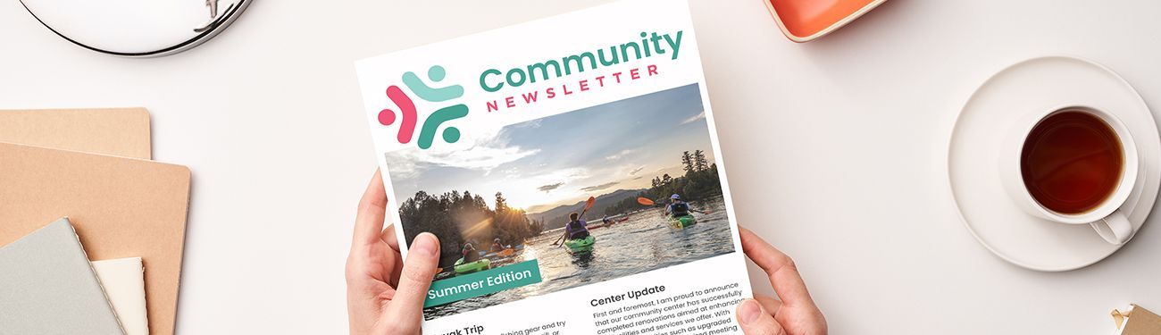 A person is holding a community newsletter in their hands.
