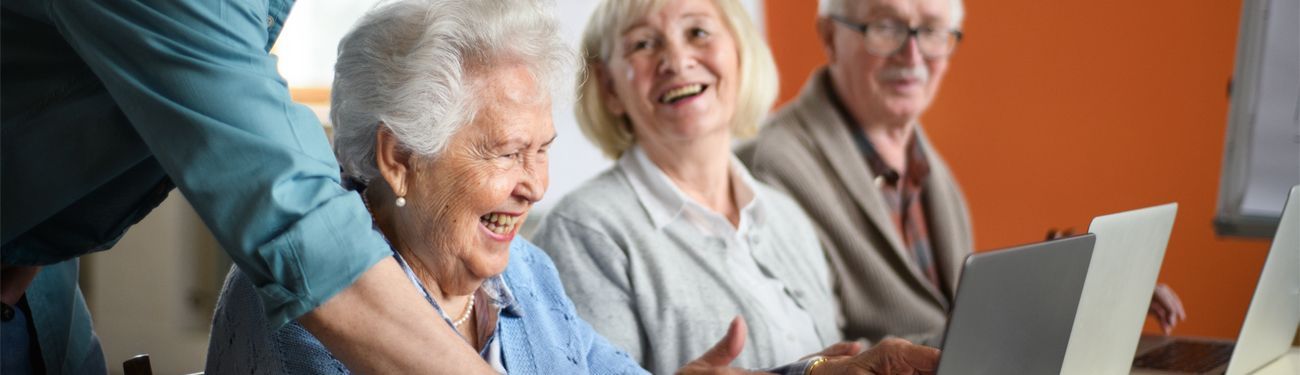 A group of elderly people are sitting in front of a laptop computer.