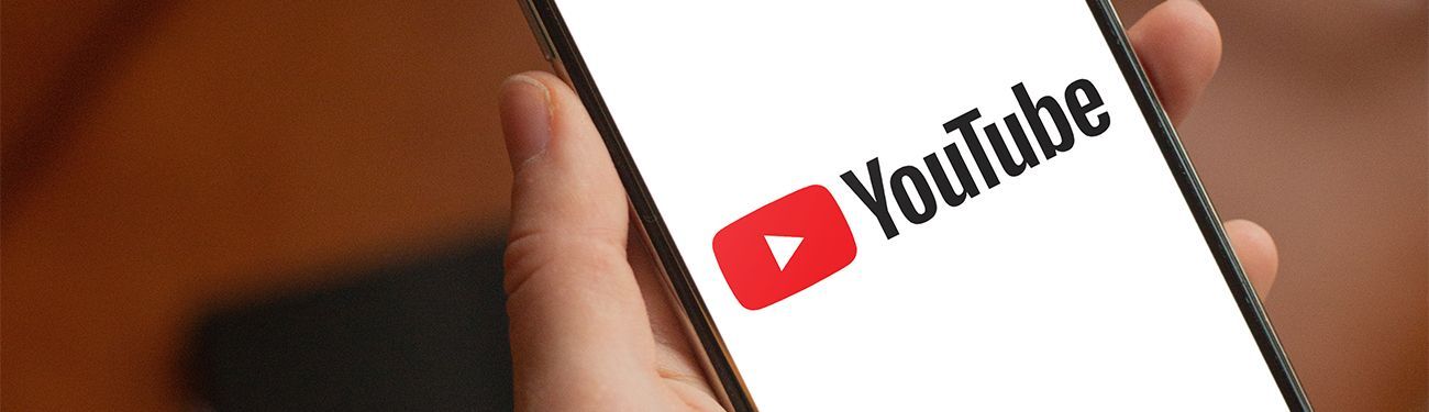 A person is holding a cell phone with the youtube logo on the screen.