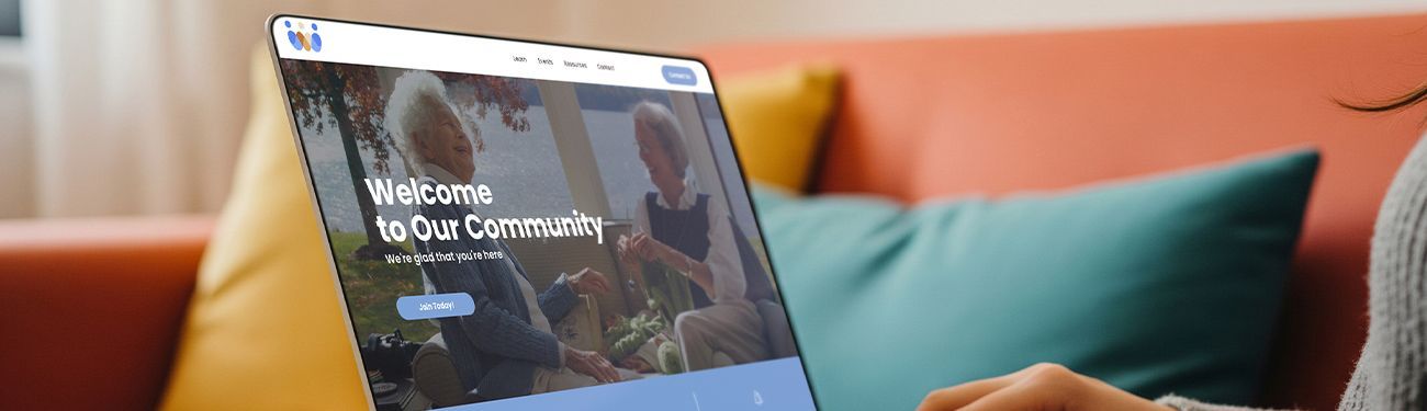 Two women sitting on a couch reading a newsletter, smiling. 