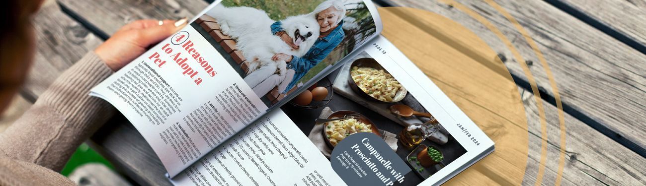 A person is reading a magazine on a wooden table.
