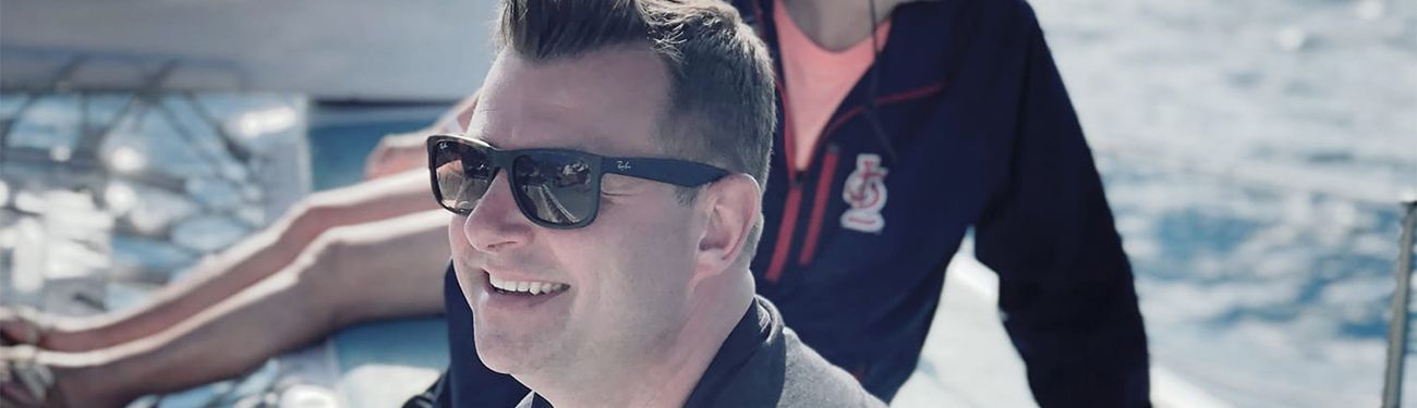 Matt Inkmann sitting on a beach in sunglasses.