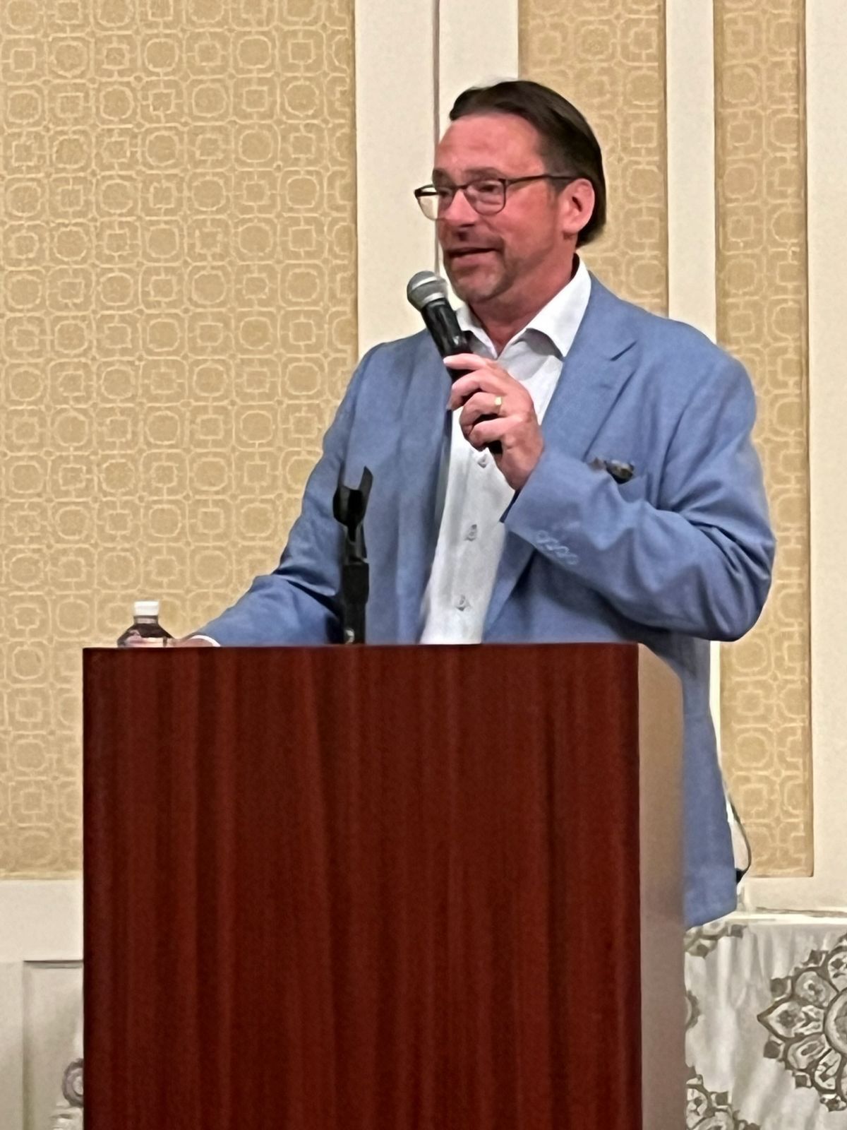 A man is standing at a podium holding a microphone.
