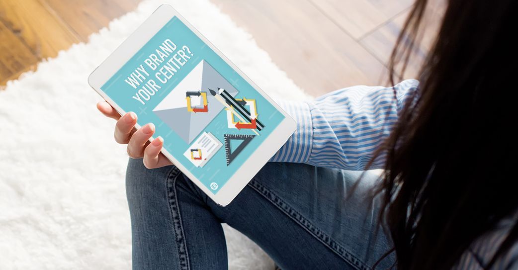 A woman is sitting on the floor holding a tablet.