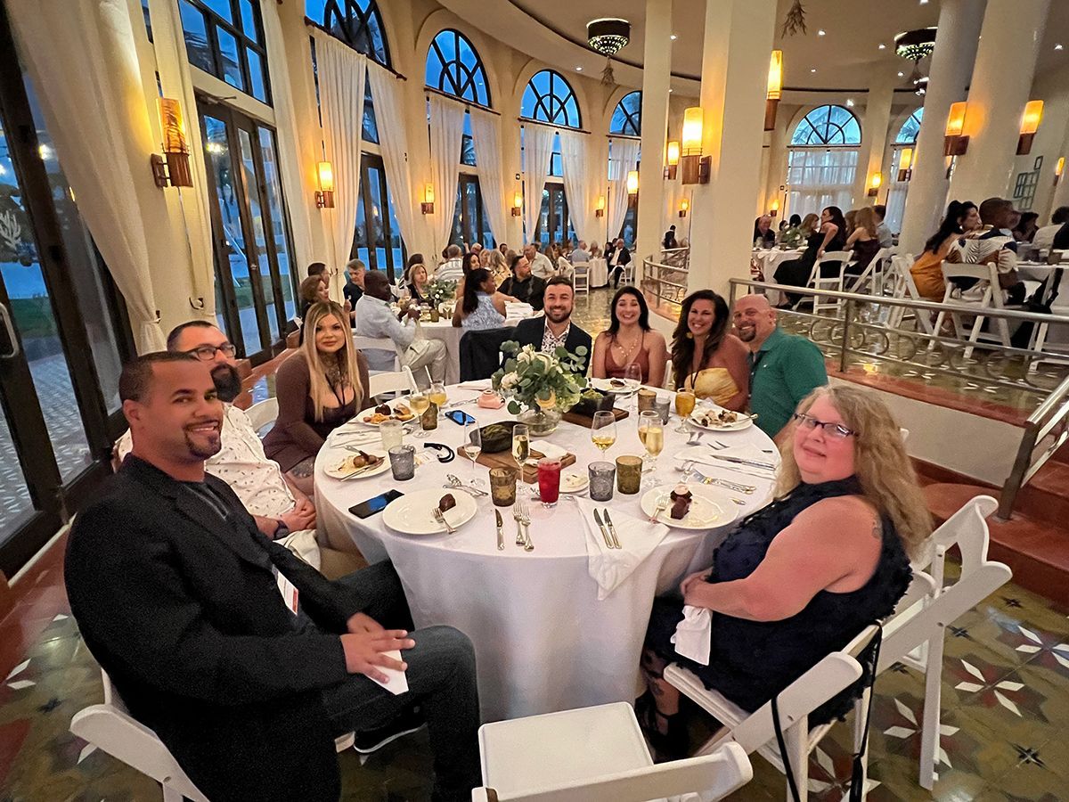 A group of people are sitting around a table in a large room.