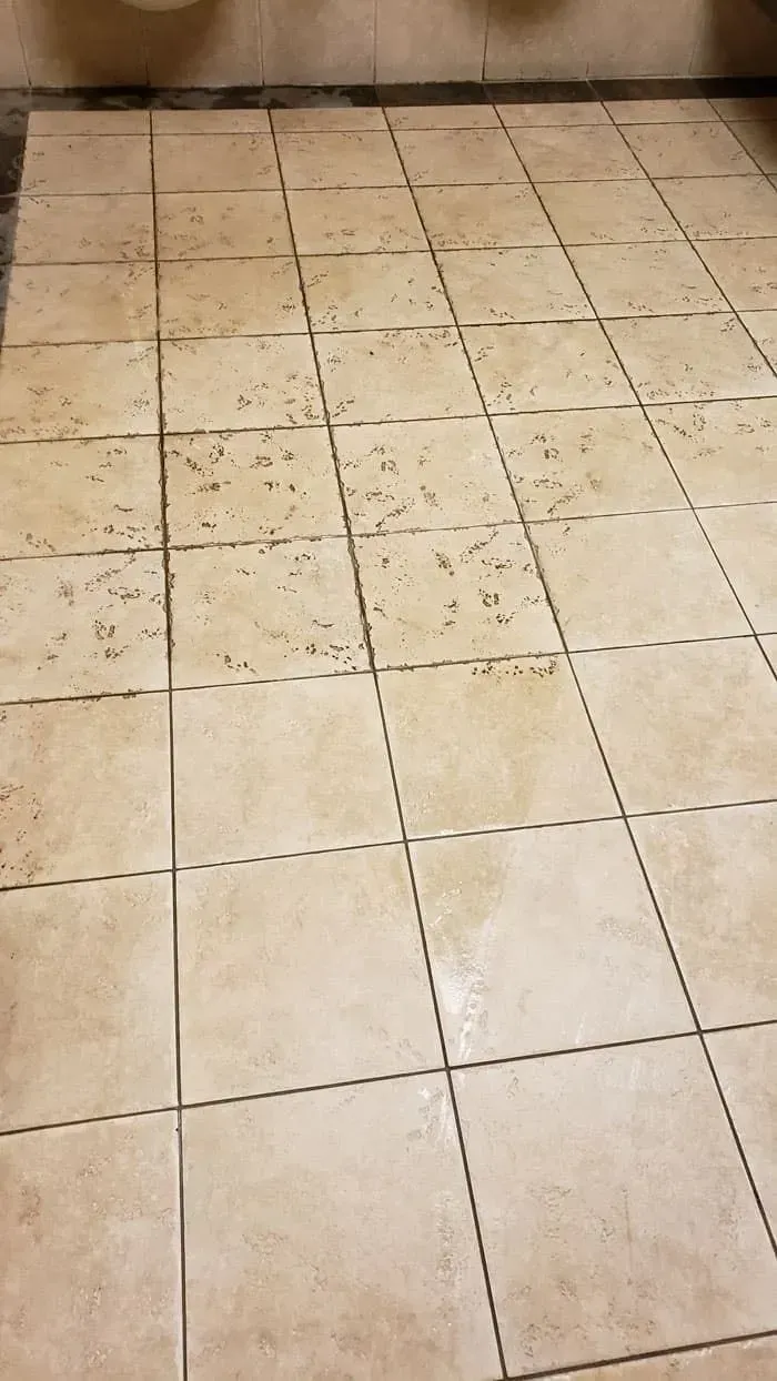 Beige tiled floor with multiple stains and marks, likely from water or dirt.