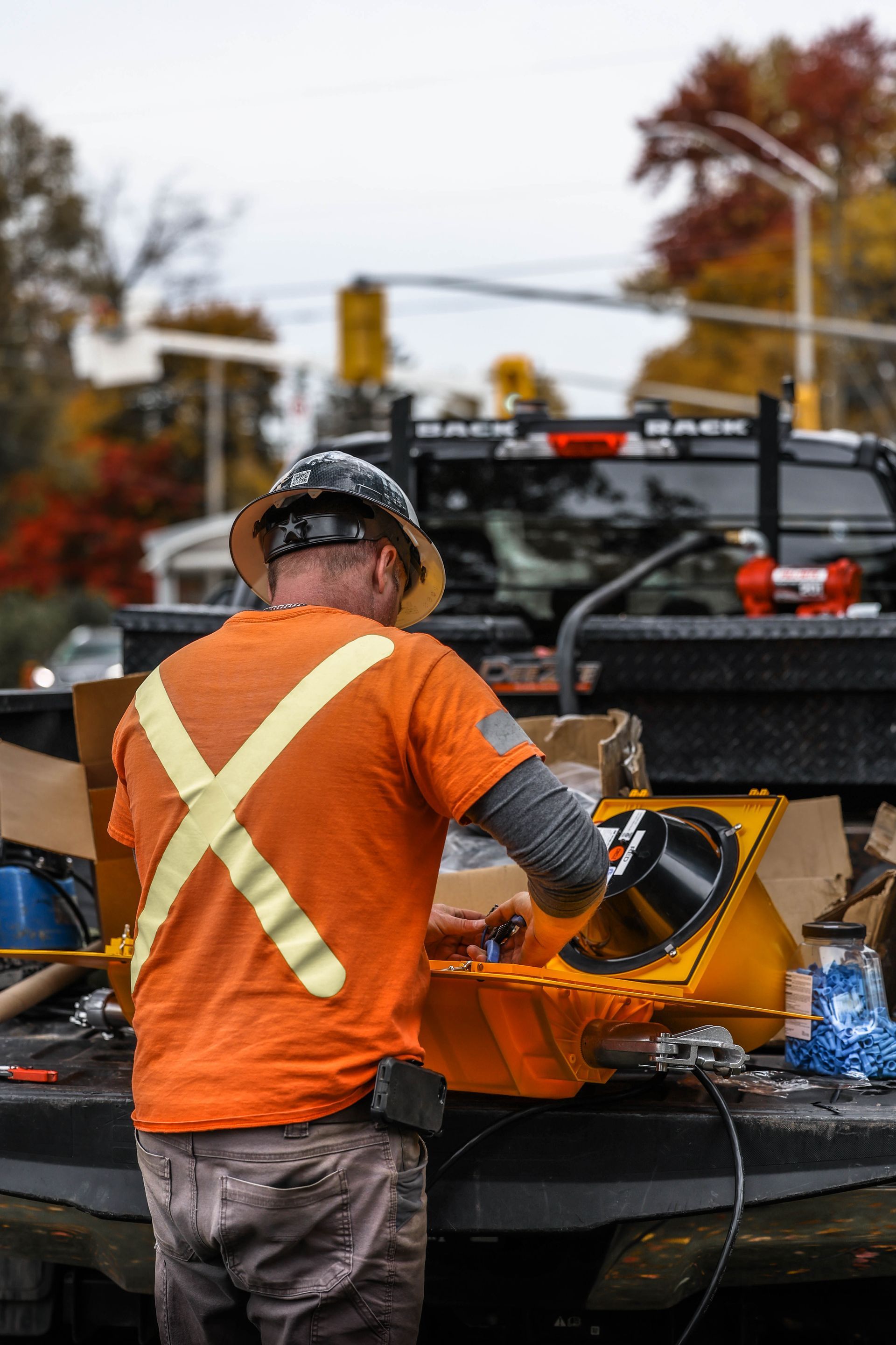 A man in an orange shirt and hard hat is working on a machine.