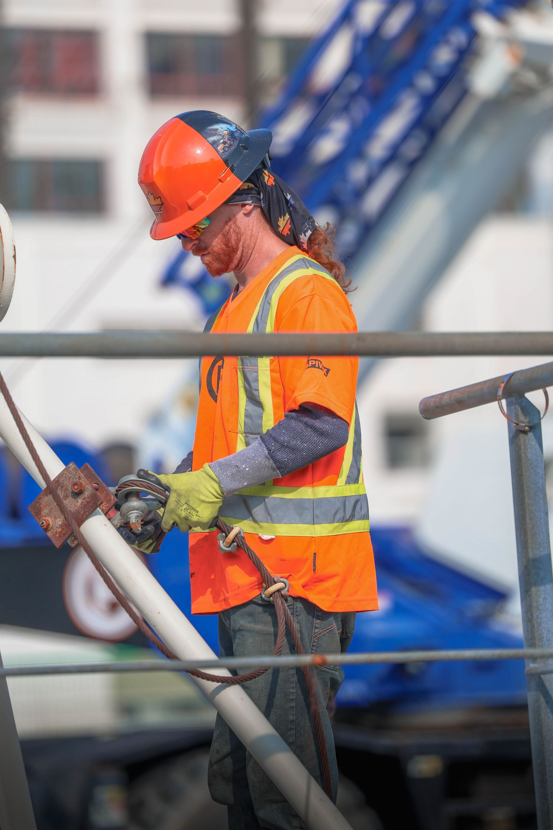 a construction worker wearing a hard hat and safety vest is working on a pipe .
