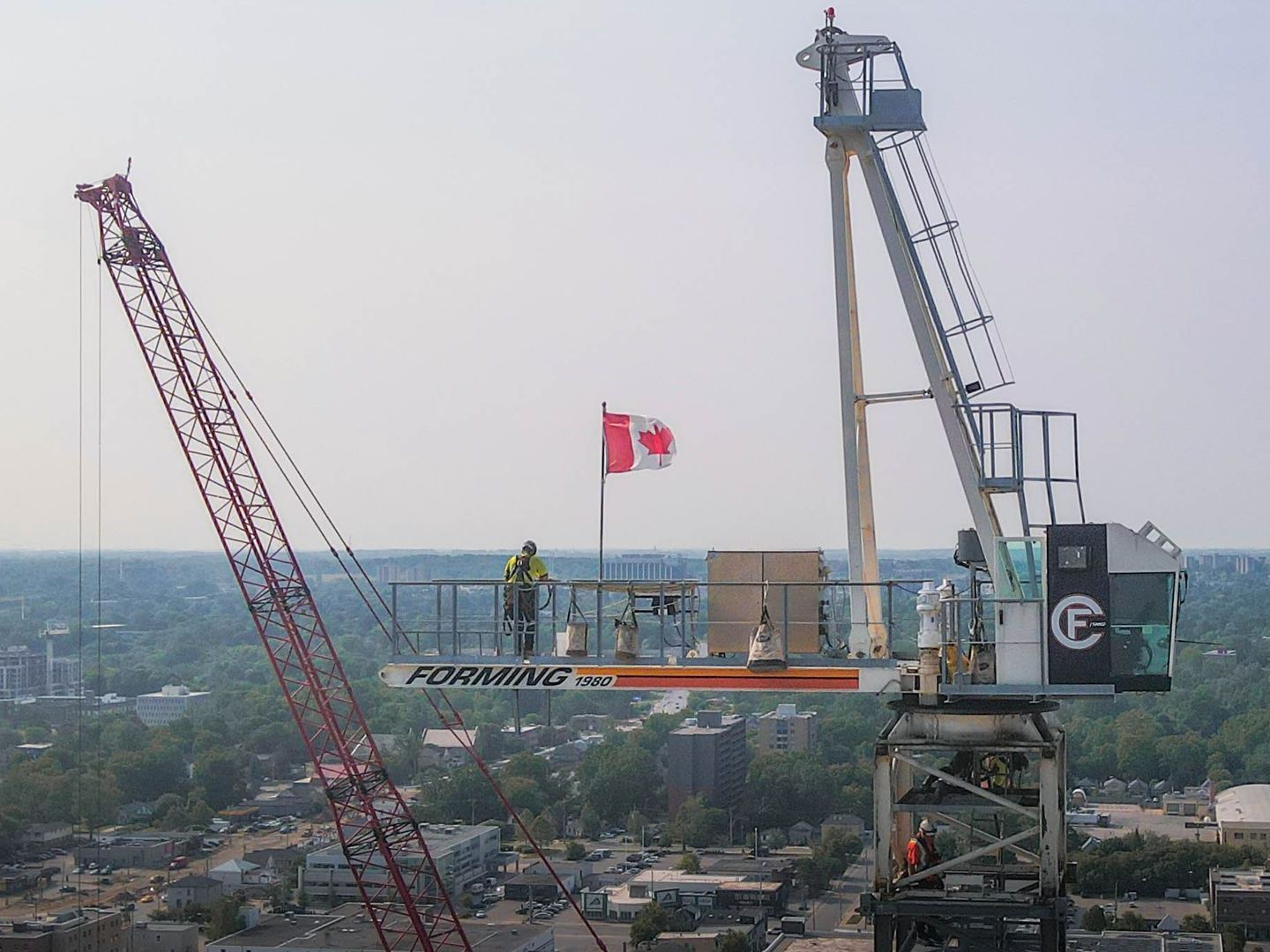 a construction crane with a canadian flag on top of it