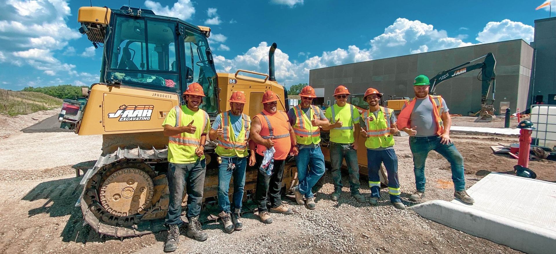 a group of construction workers are posing for a picture in front of a bulldozer with J-AAR career opportunities