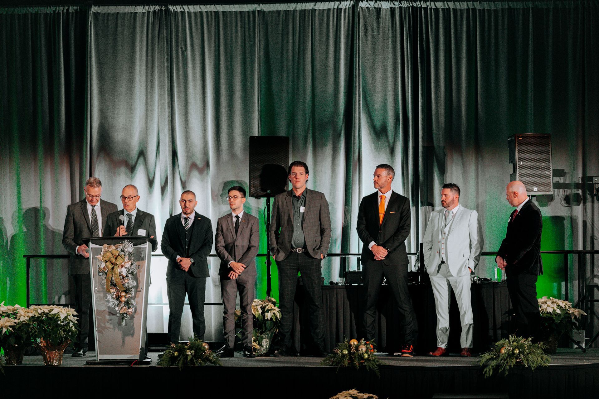 a group of men in suits are standing on a stage .