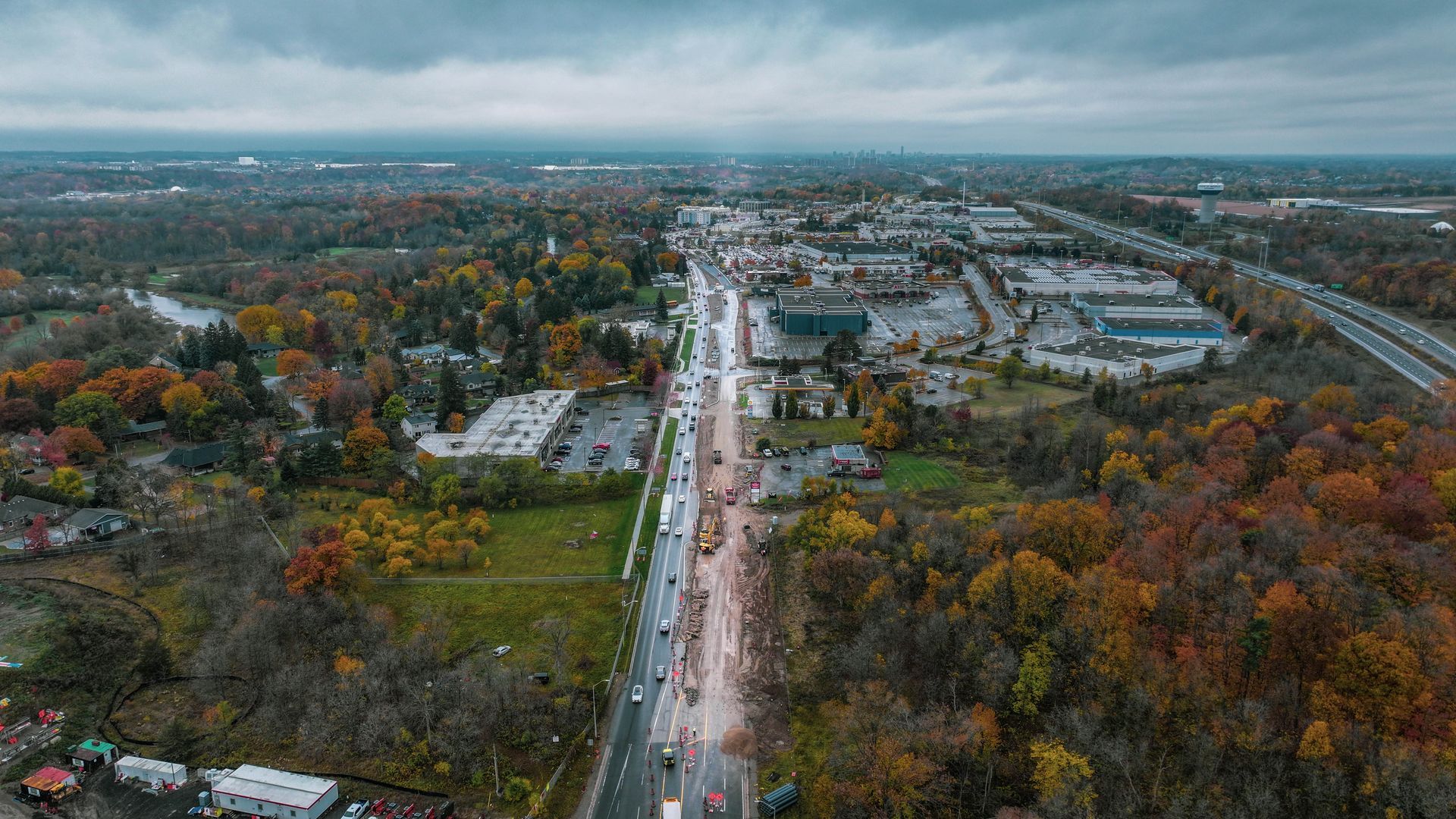An aerial view of a city surrounded by trees and a highway.