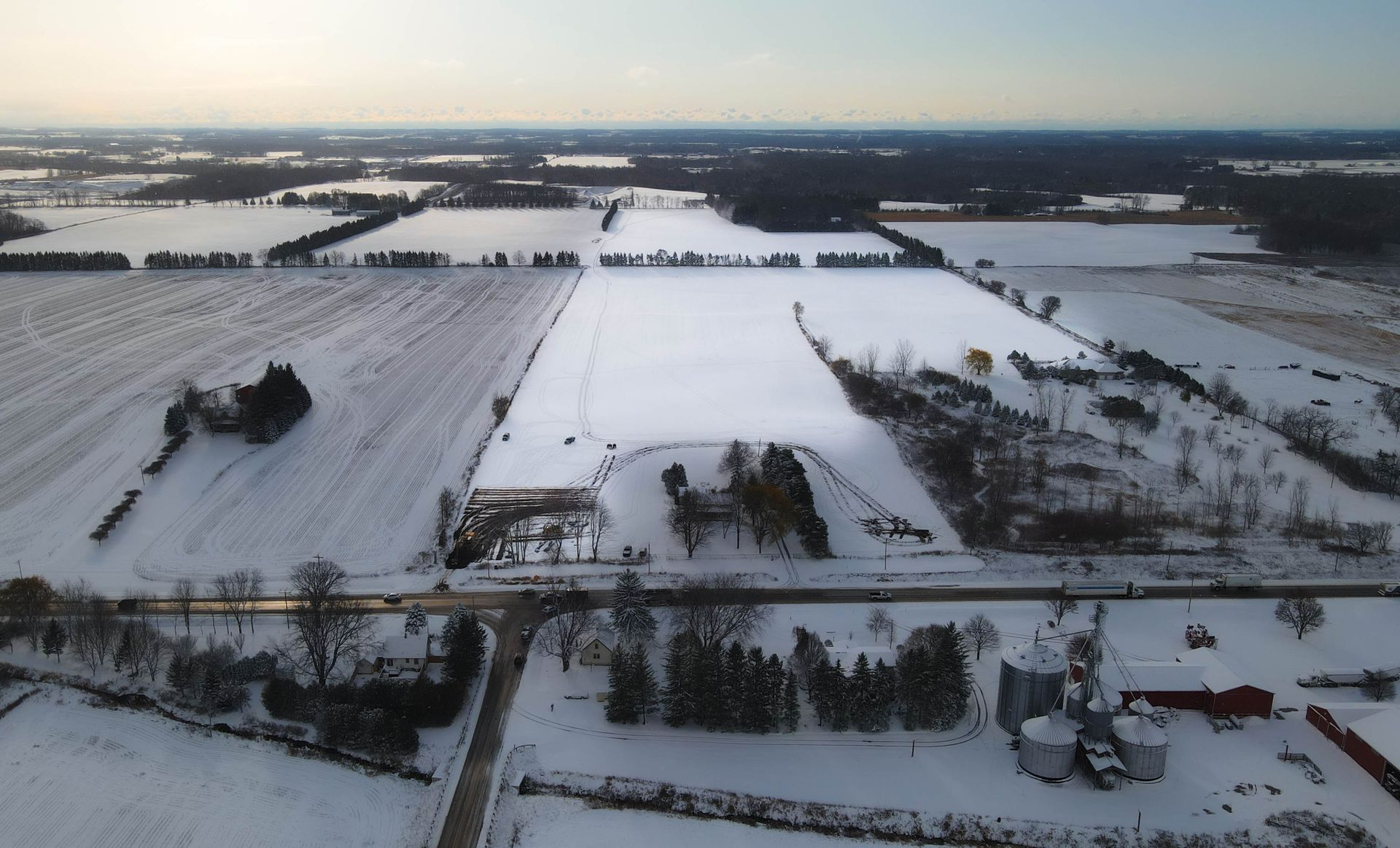 an aerial view of a snowy landscape with a farm in the foreground