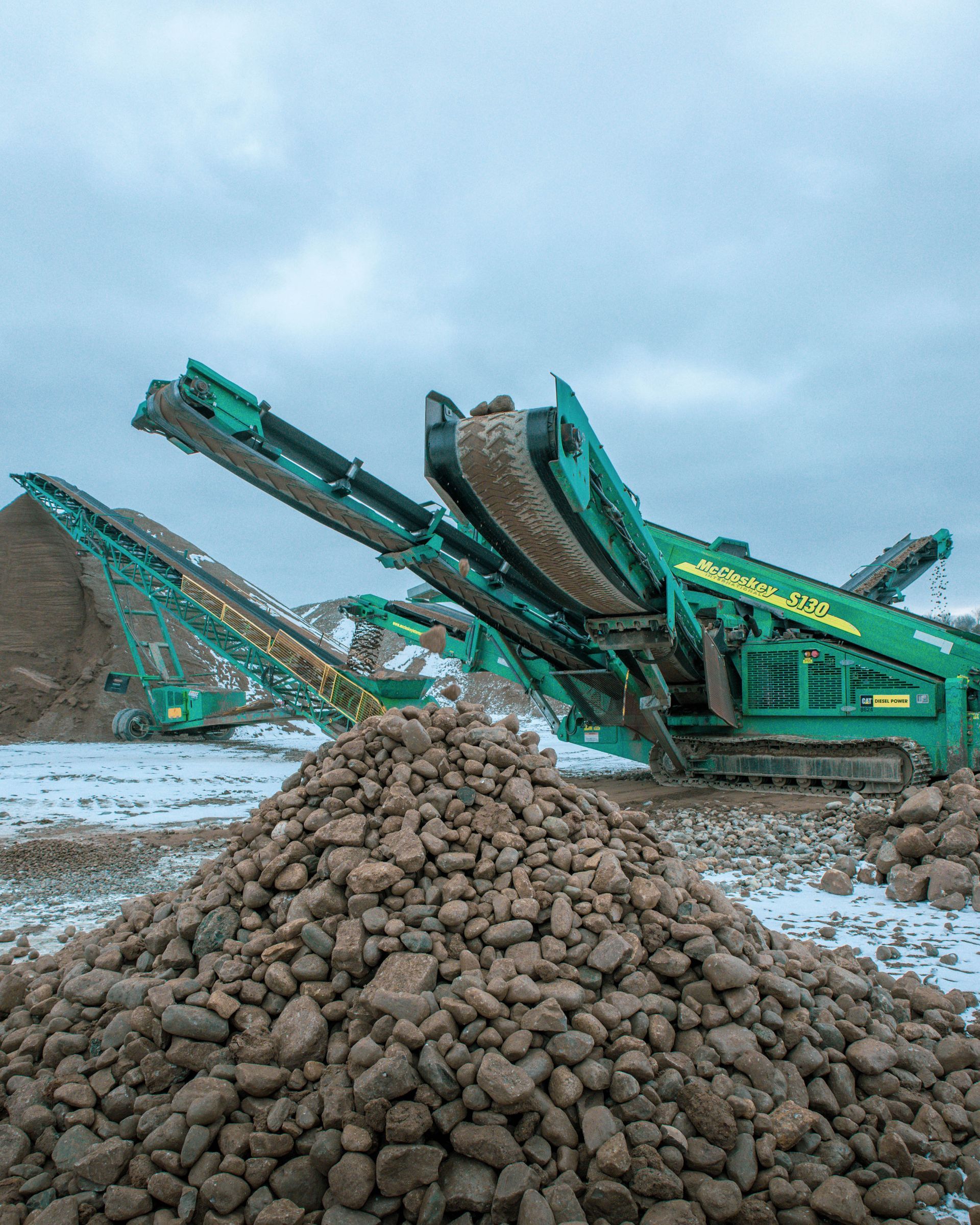 a green machine is sitting on top of a pile of rocks .